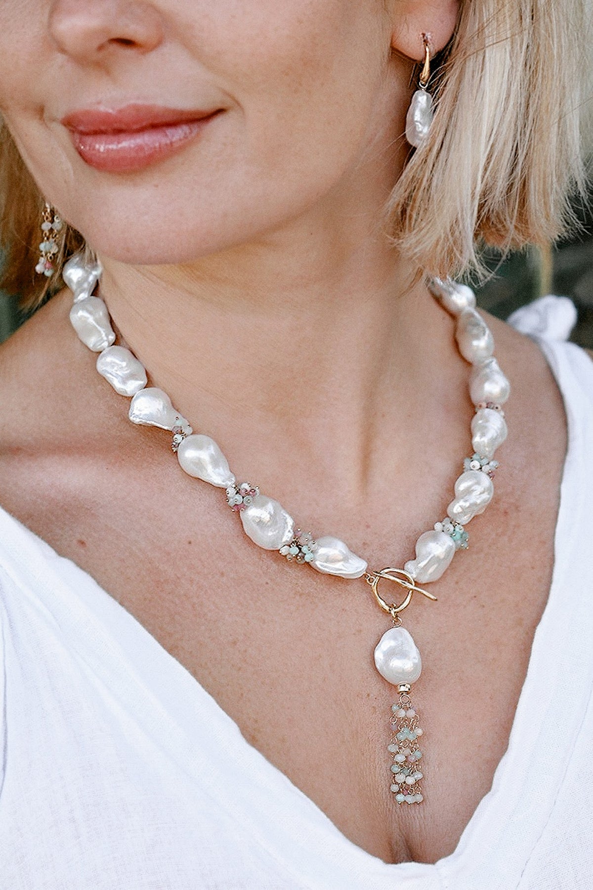 Close-up of Fiora freshwater baroque pearl necklace with gold toggle clasp and delicate gemstone clusters
